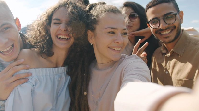 A group of five people taking a selfie outdoors under a clear blue sky.